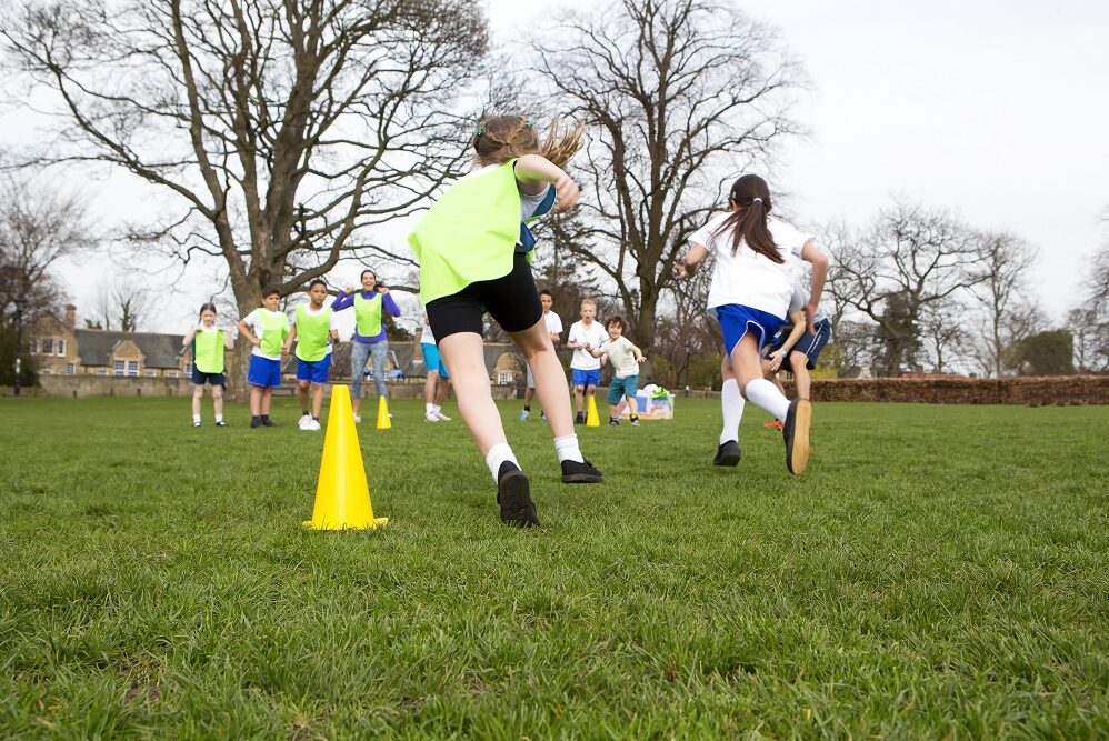 School,Children,Wearing,Sports,Uniform,Running,Around,Cones,During,A